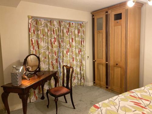 科芙Self Catering Apartment- 11A Westbourne Place的一间卧室配有书桌、镜子和床