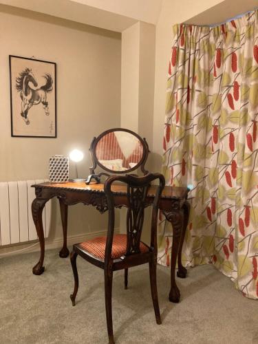 科芙Self Catering Apartment- 11A Westbourne Place的一张桌子、椅子和一张带镜子的桌子