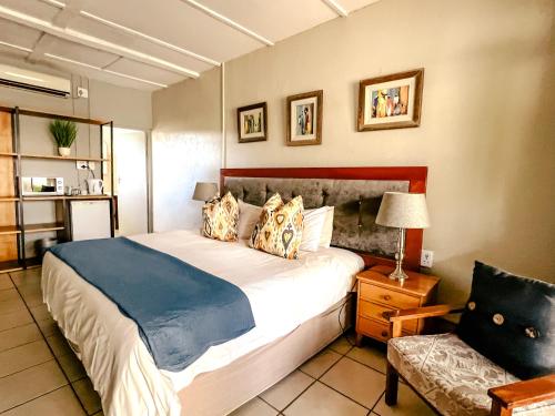 MkuzeBiweda Nguni Lodge的一间卧室配有一张大床和一把椅子