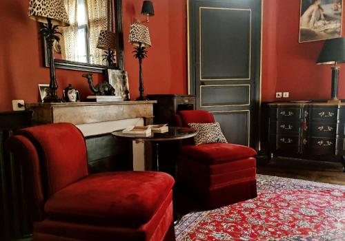 南特Le 1825, une suite luxueuse au coeur de la ville的客厅设有红色的墙壁、椅子和桌子