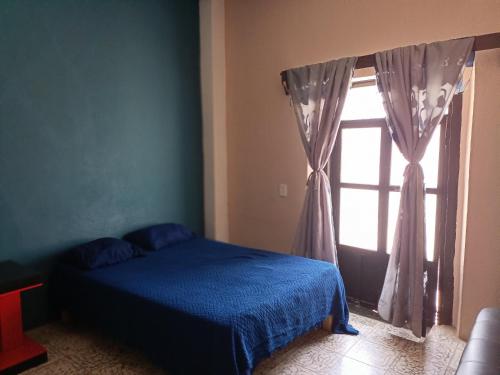 萨卡特卡斯Casa Flores的一间卧室设有蓝色的床和窗户。