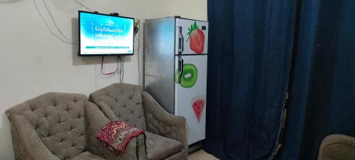 阿莱曼الساحل الشمالي的客房设有电视、两把椅子和一台冰箱