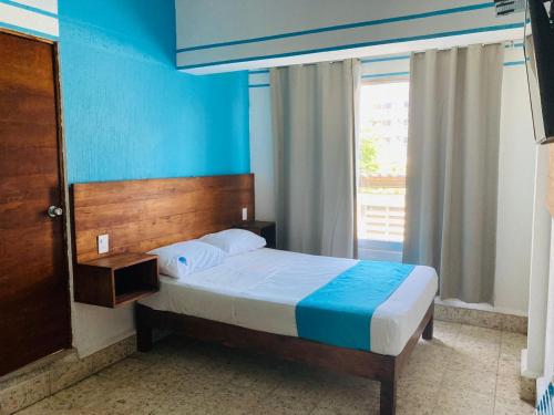 阿卡普尔科Hotel Lu Acapulco的一间卧室配有一张蓝色墙壁的床和一扇窗户
