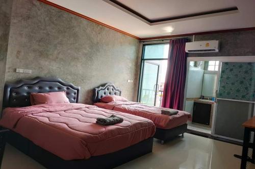 Ban Non KumPingpong Place的一间卧室设有两张带红色床单的床和窗户。