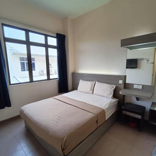 马六甲Park City Motel的一间卧室配有一张带窗户的床和一张书桌