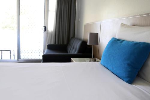 巴特曼斯贝佐巴海滨汽车旅馆的一间卧室配有一张带蓝色枕头的床和一张沙发