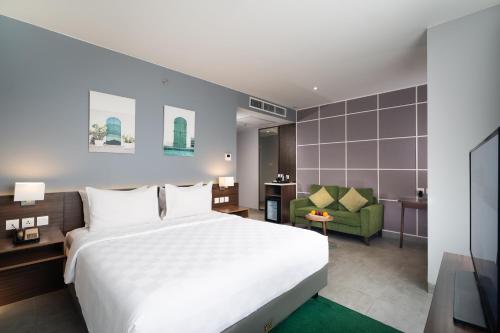茂物Swiss-Belinn Bogor的卧室配有白色的床和绿色椅子