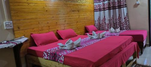 帕罗林ALEGRO HOLIDAY HOMES的配有粉红色床单和枕头的客房内的两张床