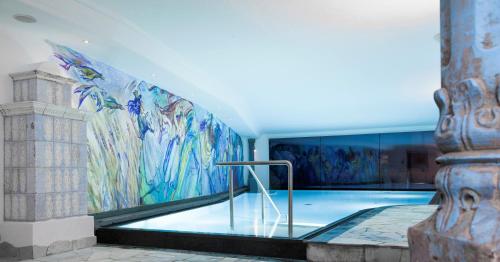 圣克里斯蒂娜贝鲁德伊多伏酒店的墙上挂有壁画的游泳池