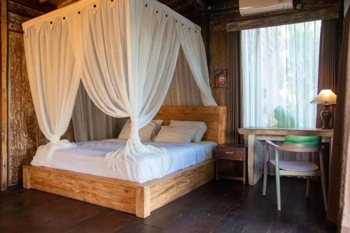 乌布Ubud Lestari Villa的一间卧室配有一张天蓬床和一张桌子