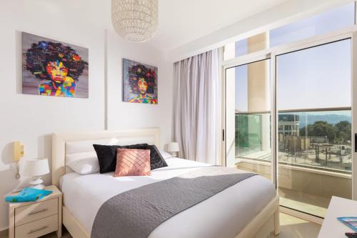 埃拉特YalaRent Golf Residence 3BR apt in luxury complex with pool的一间卧室设有一张床和一个大窗户