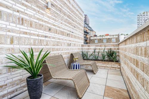 伦敦JOIVY Luxury flats near Big Ben and London Eye的庭院里摆放着两把椅子,种植了盆栽植物
