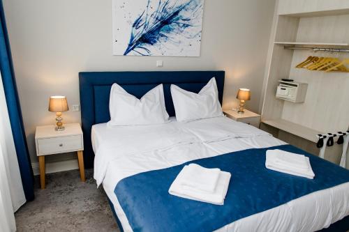 塔勒Aneton Garni Hotel的卧室配有蓝色和白色的床,提供毛巾