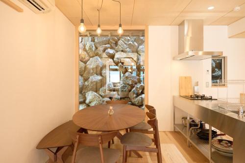OchiCarpe Diem Kamaida的一间设有木桌和石墙的用餐室
