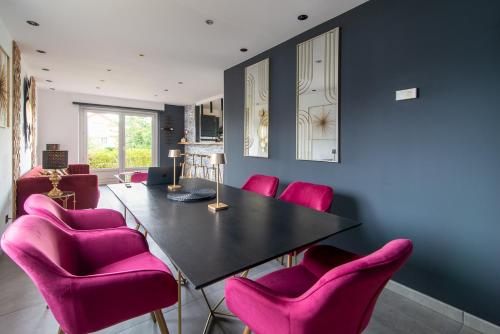 StaffelfeldenGîte au coeur de l'Alsace Maison Gatsby的用餐室配有粉红色的椅子和黑桌
