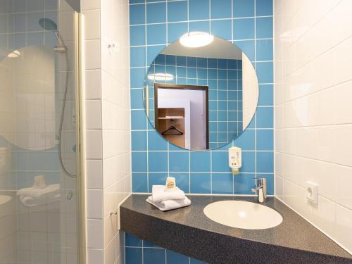 杜伊斯堡B&B Hotel Duisburg Hbf-Süd的蓝色瓷砖浴室设有水槽和镜子