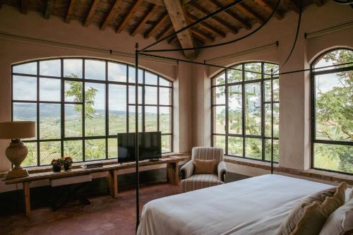芬奇Exclusive Wine Resort - Villa Dianella的一间卧室设有一张床、一台电视和窗户。