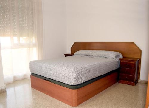 特拉萨Apartamentos Atlas Terrassa IV (Les Escoles)的卧室内的一张床铺,配有木制床架