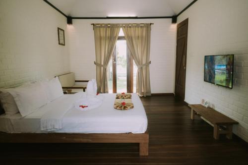 KangkakawalThe Kelong Trikora Resort的卧室配有白色的床和窗户。