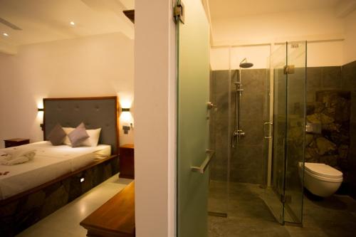 贝鲁沃勒Lena Resort的浴室设有床铺和玻璃淋浴间。