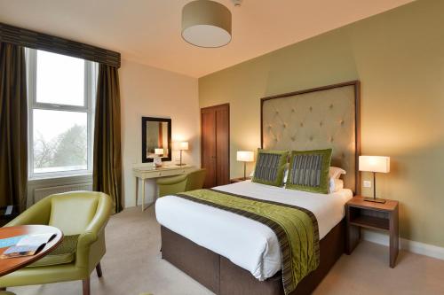 罗奇代尔曼彻斯特诺顿格兰治Spa美居酒店的酒店客房带一张大床和一把椅子
