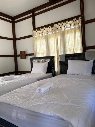 卡里蒙贾瓦Dewa Daru Resort的一间卧室设有两张带白色床单的床和窗户。