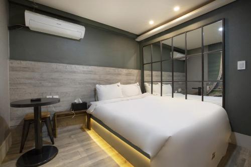 釜山SoL Hotel的卧室配有一张白色的大床和一张桌子
