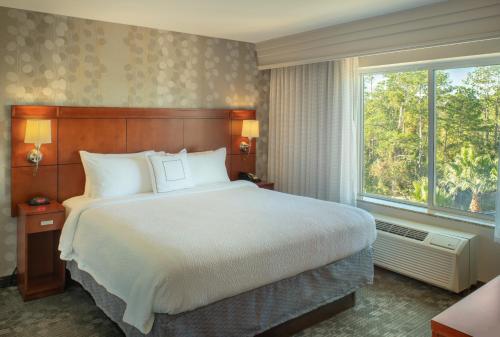 橘园杰克逊维尔橘园万怡酒店的一间卧室设有一张大床和一个大窗户