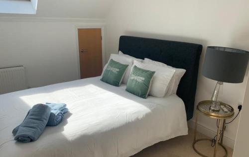 阿德尔斯通Addlestone - Large Stunning 2 bed room Apartment的卧室配有白色床和绿色和白色枕头