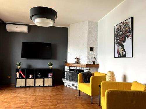 贝拉诺La Bella Vita Bellano Lakeview的客厅配有黄色椅子和平面电视
