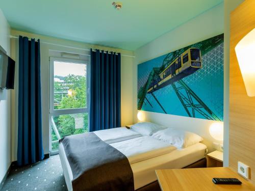 伍珀塔尔B&B HOTEL Wuppertal City-Süd的一间卧室配有一张床铺,墙上挂有火车绘画