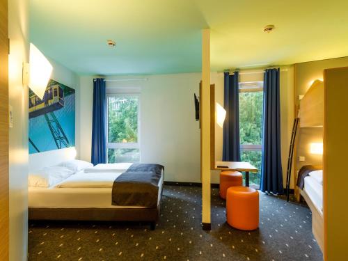 伍珀塔尔B&B HOTEL Wuppertal City-Süd的酒店客房设有一张床和两个窗户。