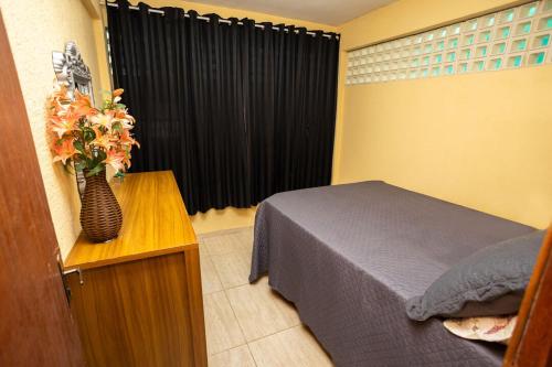 圣特雷莎Otima casa com Wi-Fi em Santa Teresa ES的一间卧室,配有一张床,桌子上放着花瓶
