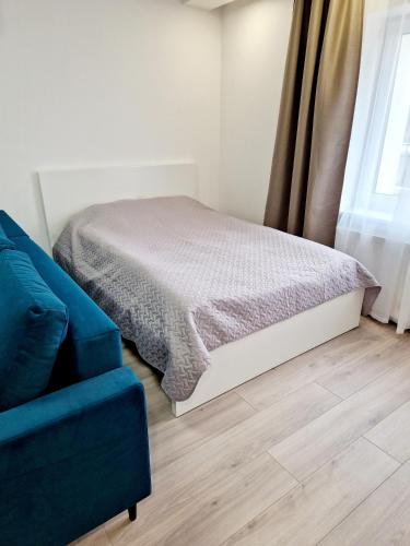 拉兹迪亚伊Apartments in Lazdijai的一间卧室配有一张床和一张蓝色的沙发