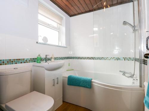 金斯林Kathy's Cottage的白色的浴室设有浴缸、卫生间和水槽。