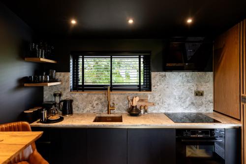 奥本The Black Cabin Oban的厨房配有带水槽的柜台和窗户。