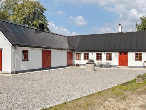 Skurup4 person holiday home in SKURUP的白色谷仓,设有红色的门和黑色的屋顶