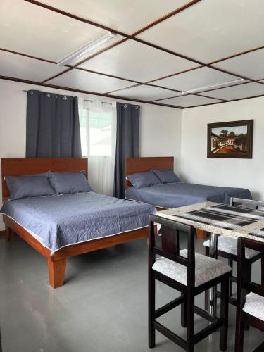 阿拉胡埃拉MARIO的一间卧室配有两张床和一张桌椅