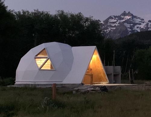 特来凡林Nomade Patagonia Glamping & Domos的田野上的小白色房子,有窗户