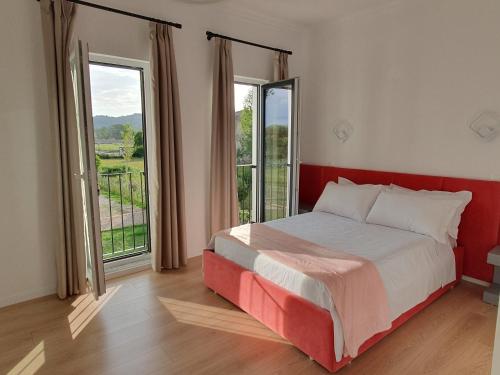 RinasNerium Garden Inn Tirana Airport的一间卧室设有一张床和两个大窗户