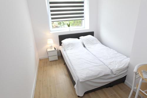 热舒夫Komfi Dom 4的一间卧室配有一张带白色床单的床和一扇窗户。