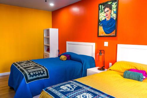 罗萨里托Hotel Cantaritos的一间卧室设有两张床和橙色的墙壁