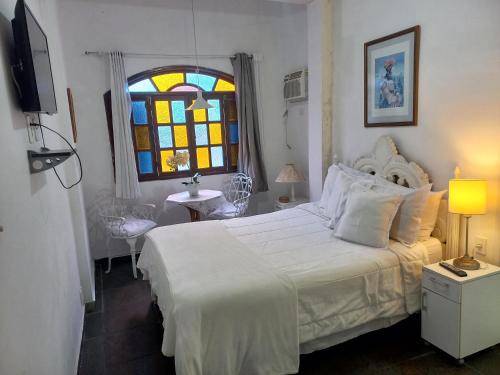曼加拉蒂巴Pousada do Sossego Conceição de Jacareí的卧室配有白色的床和彩色玻璃窗