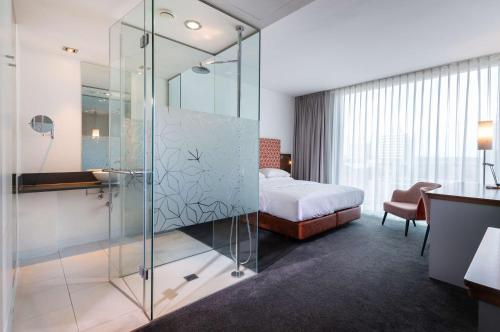 美因河畔法兰克福DoubleTree by Hilton Frankfurt Niederrad的一间带玻璃淋浴间和一张床的卧室