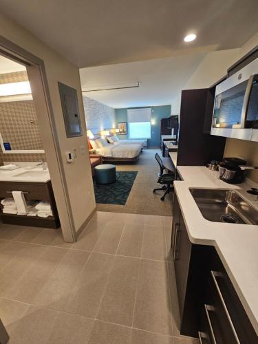伯利恒Home2 Suites By Hilton Allentown Bethlehem Airport的一间厨房和客厅,客厅内配有一张床