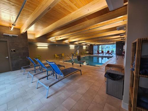 伯利恒Home2 Suites By Hilton Allentown Bethlehem Airport的一个带蓝色椅子的游泳池和一个游泳池