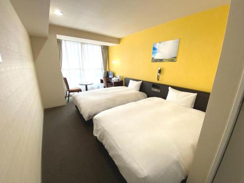府中市大陆府中酒店的两张床位于带黄色墙壁的酒店客房