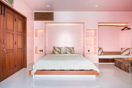 金巴兰VA Villa Jimbaran Bali的卧室配有一张带粉红色墙壁的大床