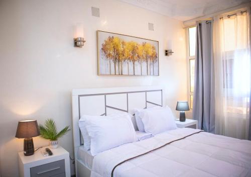 布拉柴维尔residence queen house的卧室配有白色的床和墙上的绘画作品