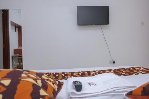 埃尔多雷特VIJIJI HOTEL & CONFERENCE的一张带T恤的床和遥控器